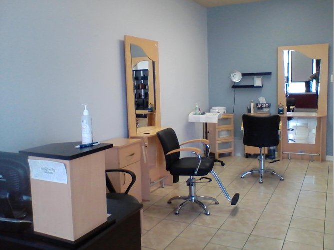 Interior of a hair salon with two styling stations, chairs, mirrors, and hairdressing equipment on tiled floor.